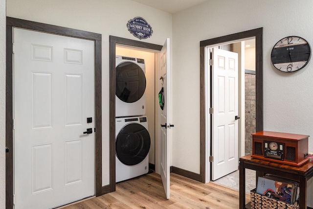 clothes washing area with stacked washer and dryer and light wood-type flooring