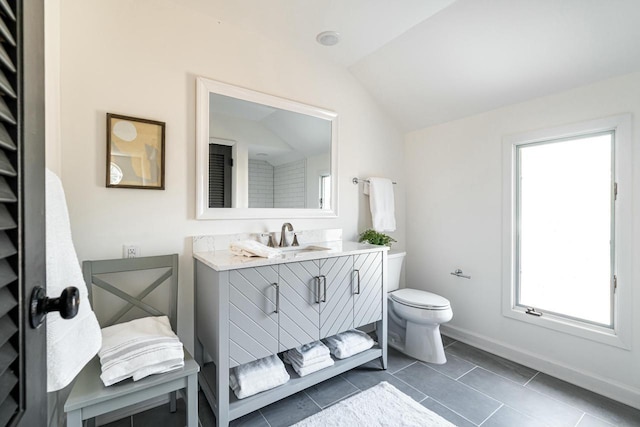 bathroom with tile patterned flooring, vanity, lofted ceiling, and toilet