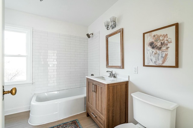 full bathroom with hardwood / wood-style flooring, tiled shower / bath, vanity, and toilet