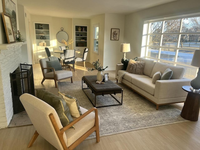 living room featuring built in features, light hardwood / wood-style floors, and a fireplace