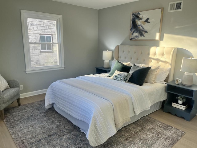 bedroom with multiple windows and wood-type flooring