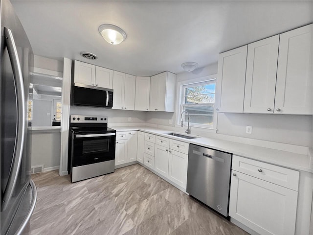 kitchen featuring stainless steel appliances, white cabinetry, and sink