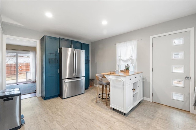 kitchen with stainless steel refrigerator, a kitchen breakfast bar, and blue cabinetry