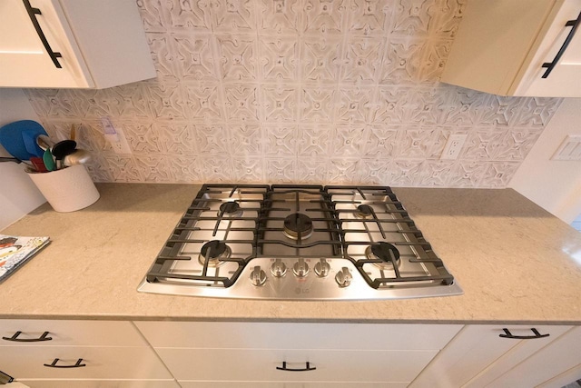 kitchen featuring light countertops, stainless steel gas cooktop, decorative backsplash, and white cabinetry