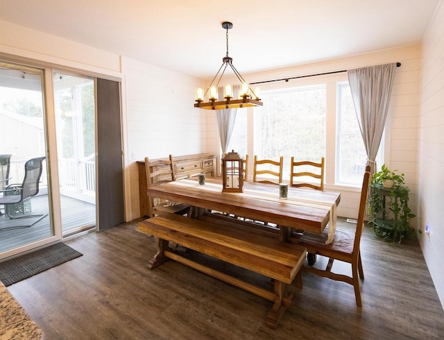 dining space with dark wood-style floors and an inviting chandelier