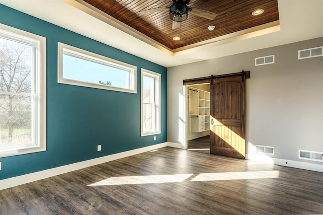 spare room with a barn door, a raised ceiling, and visible vents