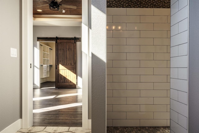 bathroom with baseboards, a ceiling fan, wood finished floors, and a textured wall