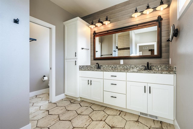 full bathroom featuring double vanity, a sink, visible vents, and baseboards