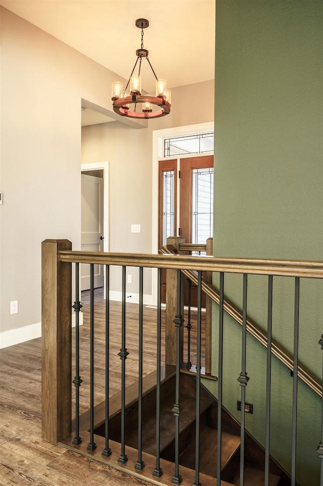 interior space with baseboards, wood finished floors, an upstairs landing, and a notable chandelier