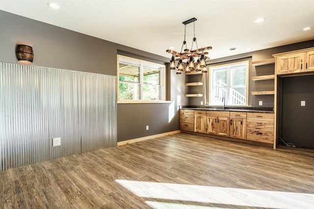 kitchen with open shelves, dark countertops, wood finished floors, a chandelier, and pendant lighting