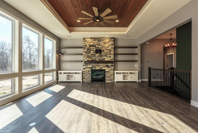 unfurnished living room featuring a raised ceiling, wood ceiling, a stone fireplace, wood finished floors, and baseboards