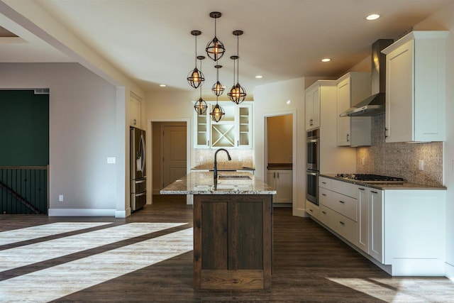 kitchen featuring white cabinets, dark wood-style floors, appliances with stainless steel finishes, wall chimney range hood, and a sink