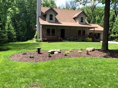 cape cod home featuring a front yard and covered porch