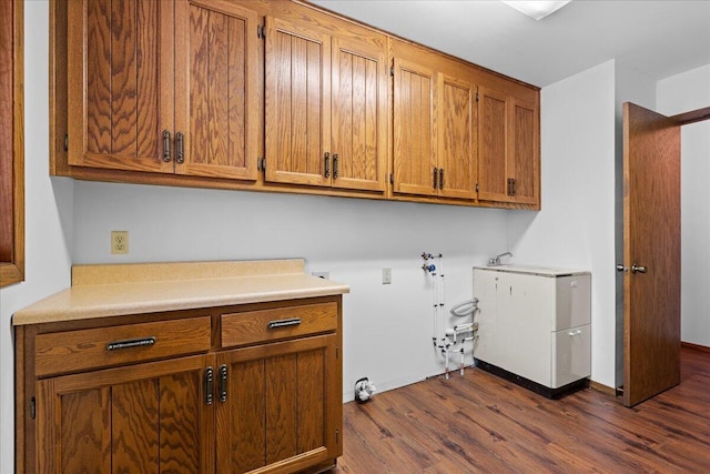 clothes washing area featuring dark hardwood / wood-style floors, washer hookup, and cabinets