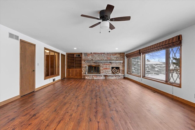 unfurnished living room with ceiling fan, hardwood / wood-style floors, built in features, and a stone fireplace