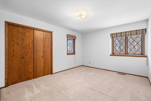 unfurnished bedroom featuring light carpet and a closet