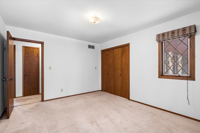 unfurnished bedroom featuring light carpet and a closet