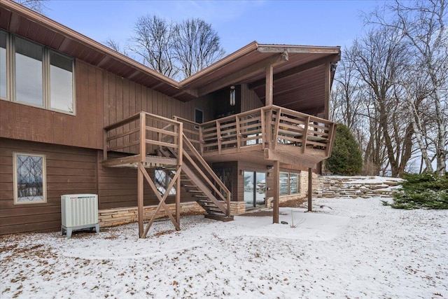 snow covered house with a wooden deck and central air condition unit