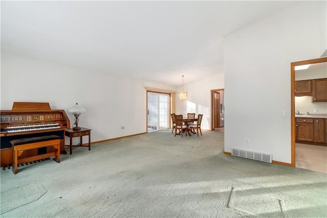 living room featuring light carpet, vaulted ceiling, sink, and a chandelier