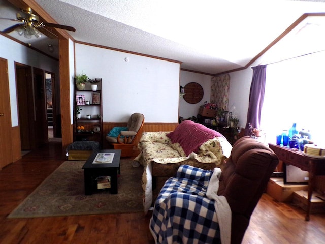 living room featuring ceiling fan, wood walls, hardwood / wood-style floors, crown molding, and a textured ceiling