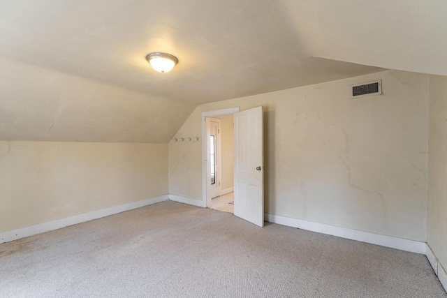 additional living space featuring lofted ceiling and light carpet