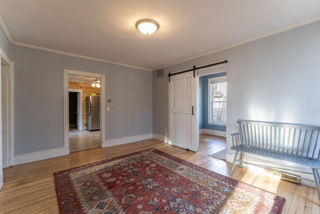 bedroom featuring stainless steel refrigerator, ornamental molding, a barn door, and light wood-type flooring