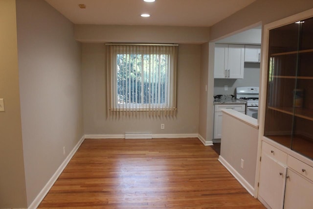 unfurnished dining area with a baseboard heating unit and light hardwood / wood-style flooring