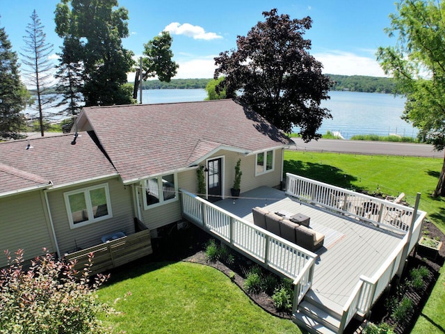 rear view of property with a deck with water view and a lawn