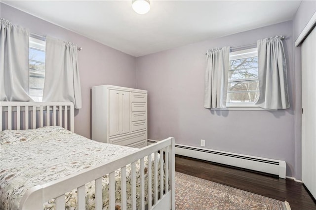 bedroom featuring a baseboard heating unit and hardwood / wood-style floors