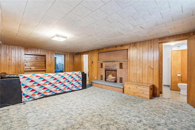 bedroom featuring ensuite bathroom, a fireplace, wood walls, and carpet floors