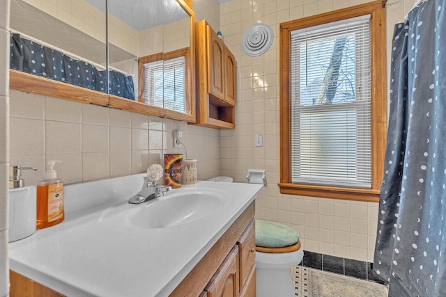 bathroom with tile walls, toilet, vanity, and a shower with curtain