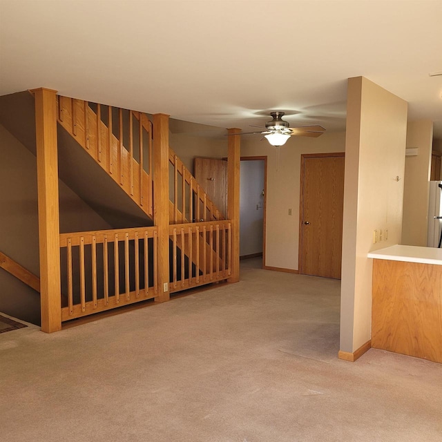 unfurnished living room featuring light carpet and ceiling fan