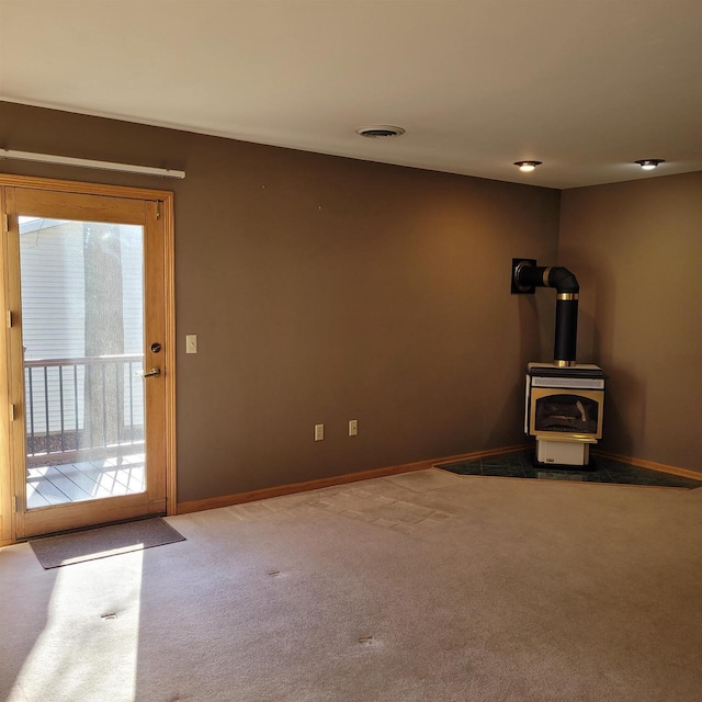 interior space featuring a wood stove, light colored carpet, and a healthy amount of sunlight