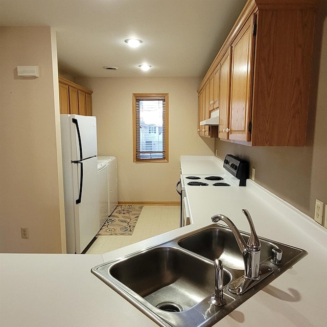 kitchen featuring independent washer and dryer, sink, and white appliances