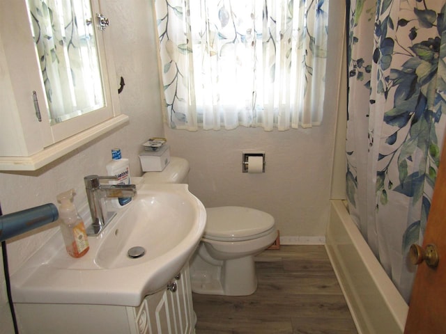 full bathroom featuring toilet, a wealth of natural light, shower / bathtub combination with curtain, and hardwood / wood-style floors