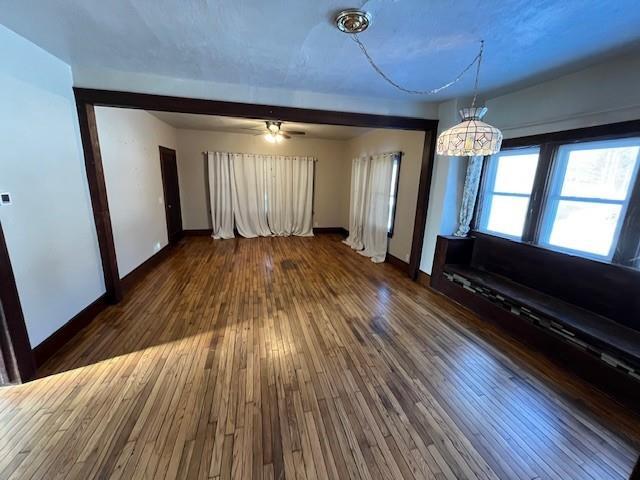 interior space with ceiling fan with notable chandelier and dark hardwood / wood-style floors