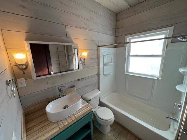 full bathroom featuring toilet, bathing tub / shower combination, wood walls, tile patterned floors, and vanity