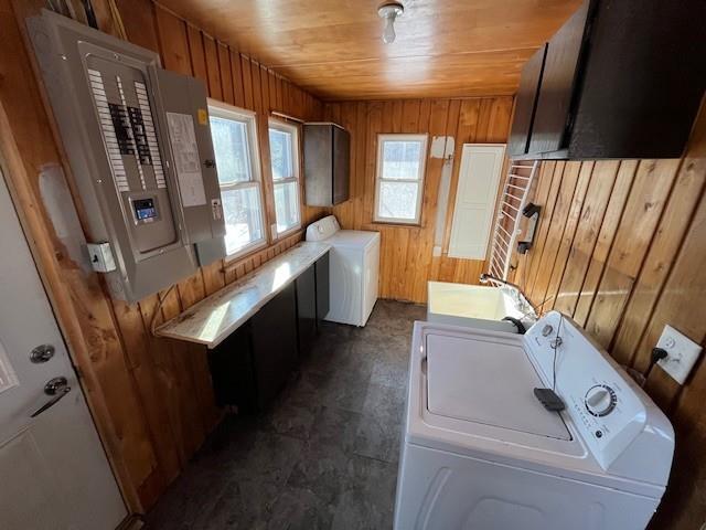 laundry room featuring electric panel, sink, wooden walls, washer and clothes dryer, and wood ceiling