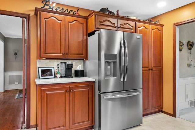 kitchen with backsplash, stainless steel fridge with ice dispenser, and crown molding