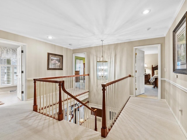 hallway with crown molding, light carpet, and an inviting chandelier