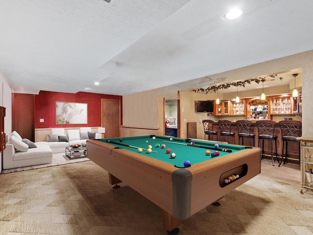 game room featuring bar area, pool table, light carpet, and a textured ceiling