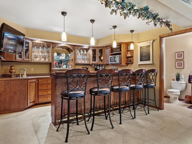 bar featuring decorative light fixtures, sink, and light tile patterned floors