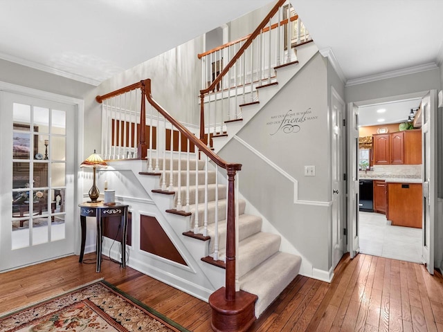 staircase with ornamental molding and hardwood / wood-style floors