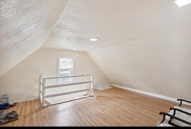 bonus room with a textured ceiling, hardwood / wood-style floors, and vaulted ceiling