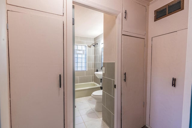 bathroom featuring toilet, tiled shower / bath combo, and tile patterned floors