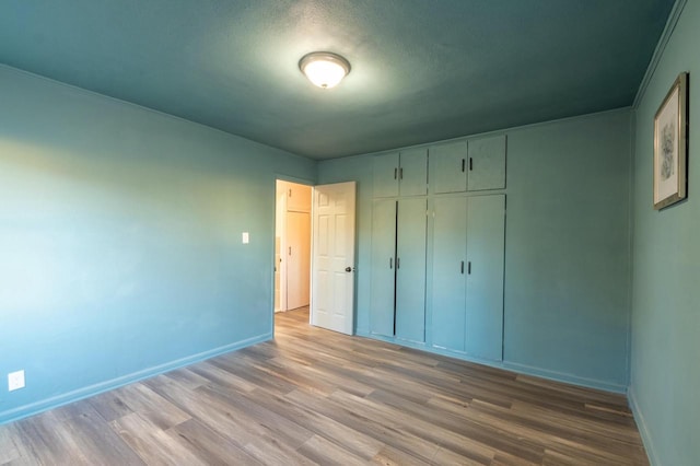 unfurnished bedroom with light wood-type flooring, a closet, and a textured ceiling