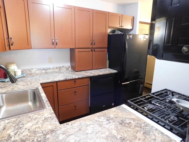 kitchen featuring light stone countertops, black appliances, and sink