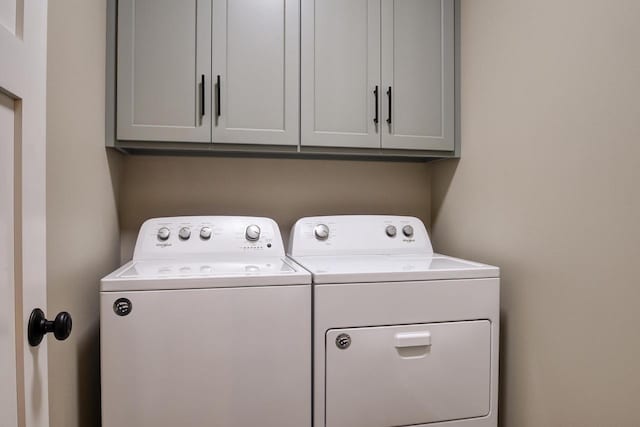 clothes washing area featuring cabinets and separate washer and dryer