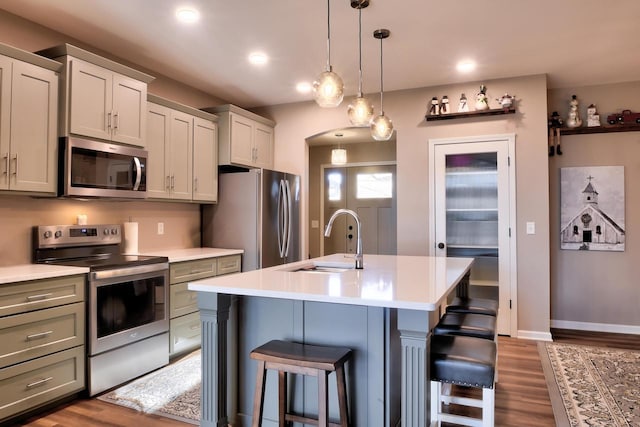 kitchen featuring a kitchen bar, sink, hardwood / wood-style flooring, a kitchen island with sink, and stainless steel appliances