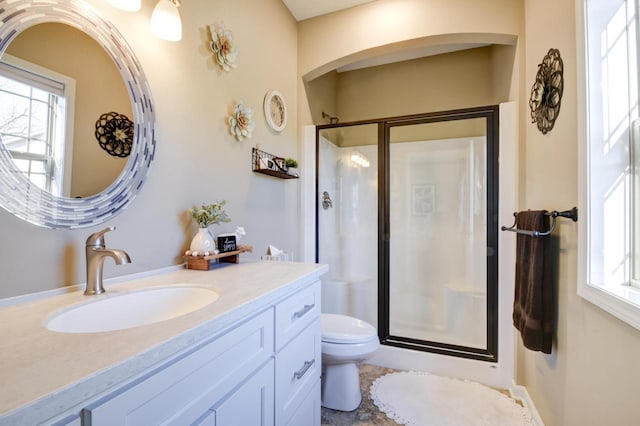 bathroom featuring vanity, toilet, plenty of natural light, and a shower with door